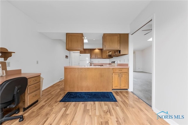 kitchen with light countertops, light wood-style floors, freestanding refrigerator, a sink, and range with electric cooktop