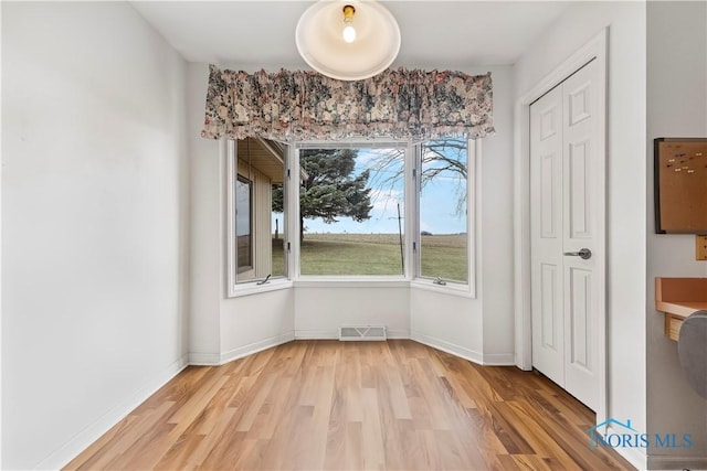 unfurnished dining area with light wood-type flooring, visible vents, and baseboards