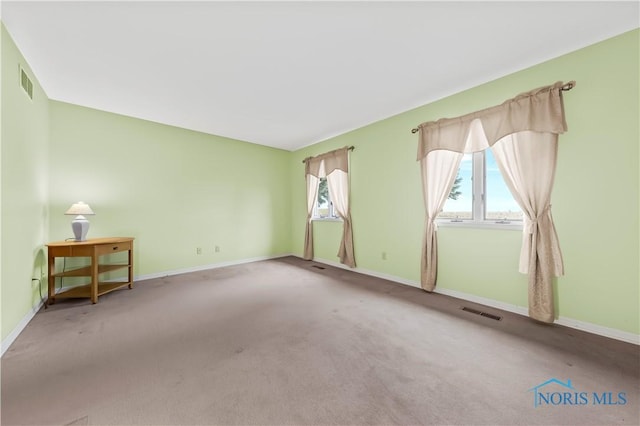 carpeted empty room with visible vents and baseboards