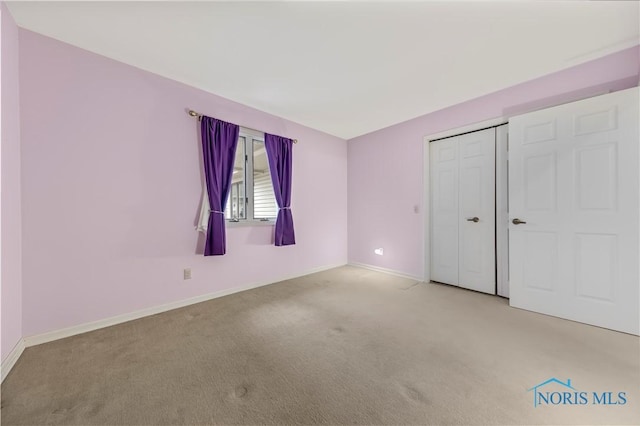 unfurnished bedroom with a closet, baseboards, and carpet flooring