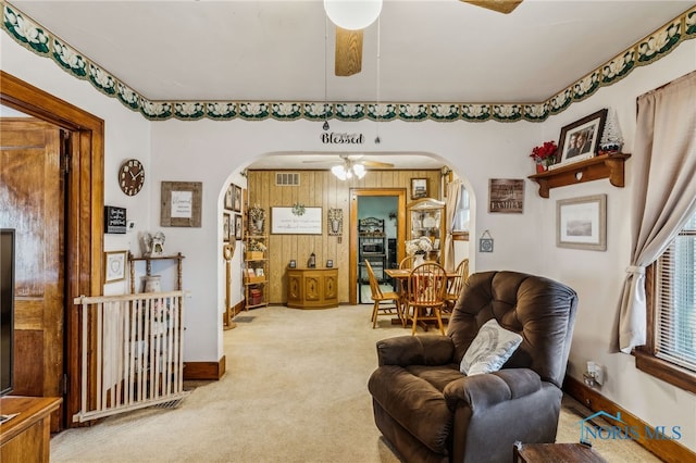 carpeted living area with a ceiling fan, arched walkways, visible vents, and baseboards