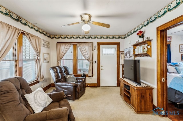 living room with ceiling fan, baseboards, and light colored carpet