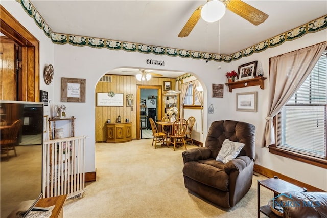 sitting room with arched walkways, carpet flooring, a ceiling fan, and baseboards