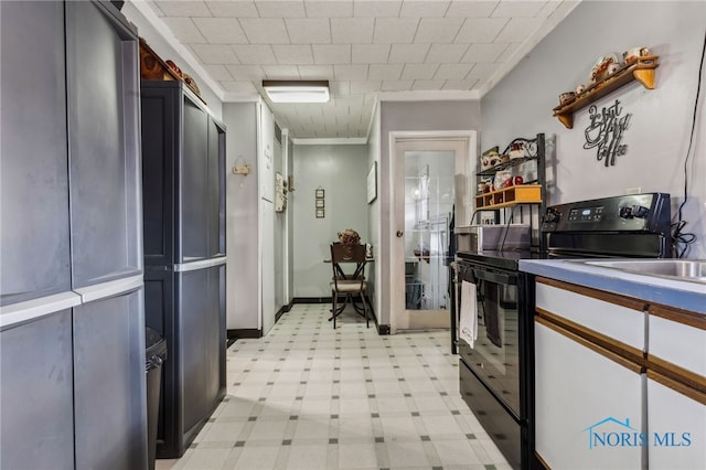 kitchen with ornamental molding, baseboards, electric range, and light floors