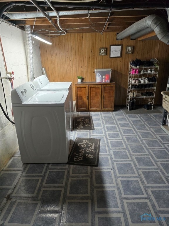 clothes washing area with concrete block wall, cabinet space, independent washer and dryer, and wooden walls