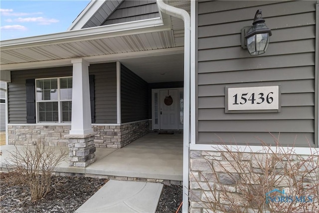 view of exterior entry featuring covered porch and stone siding