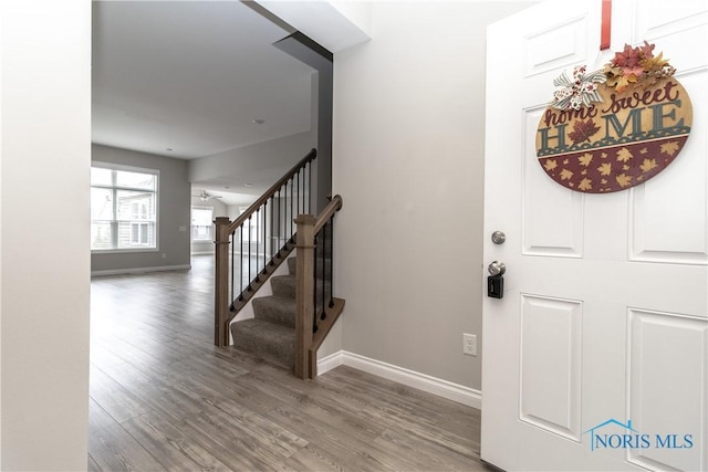 entryway with wood finished floors, baseboards, and stairs