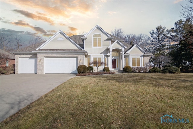 view of front facade with concrete driveway, brick siding, a lawn, and an attached garage