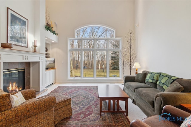 living room with built in features, a towering ceiling, and a tiled fireplace