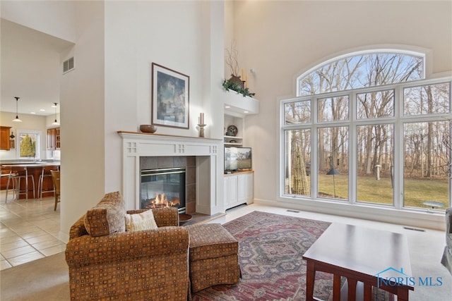 living room with built in shelves, a tile fireplace, a healthy amount of sunlight, and light tile patterned floors