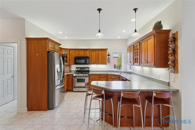 kitchen featuring brown cabinets, a peninsula, a sink, stainless steel appliances, and backsplash