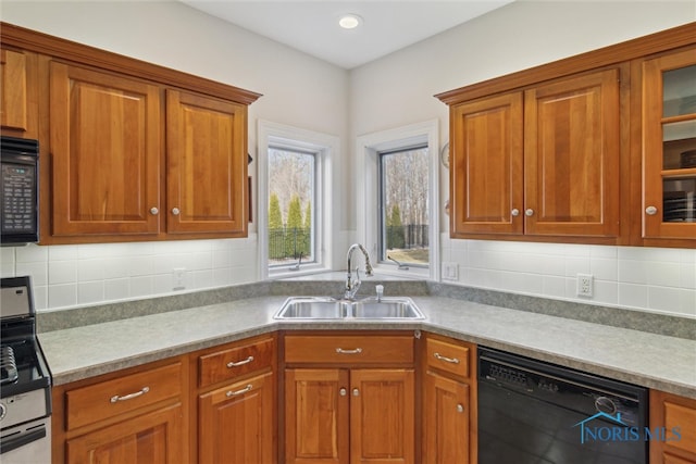 kitchen with black appliances, glass insert cabinets, brown cabinets, and a sink