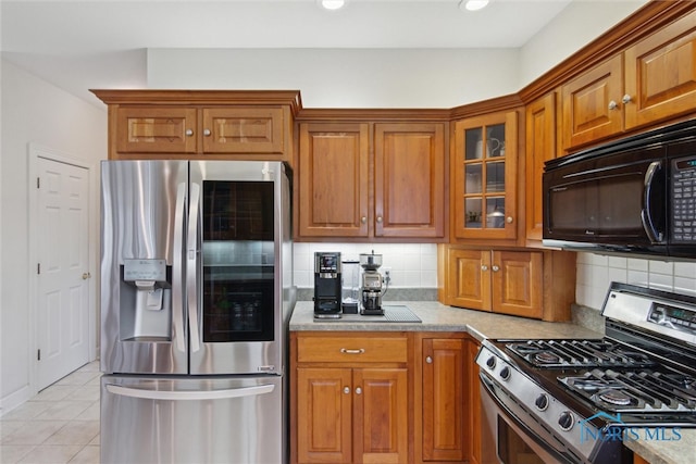 kitchen with brown cabinets, light tile patterned floors, stainless steel appliances, and decorative backsplash