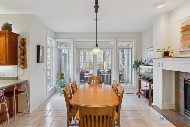 dining room with light tile patterned flooring, a fireplace, and baseboards