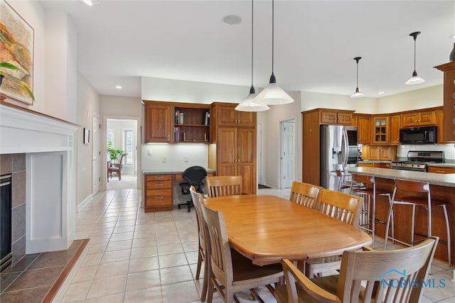 dining space featuring a fireplace, light tile patterned floors, recessed lighting, built in study area, and baseboards