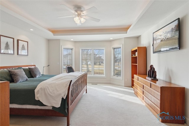 bedroom featuring baseboards, a raised ceiling, a ceiling fan, light colored carpet, and recessed lighting