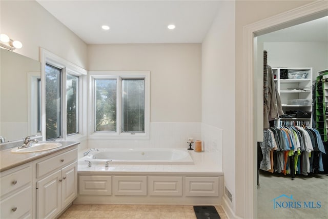 bathroom featuring visible vents, a garden tub, a walk in closet, vanity, and recessed lighting