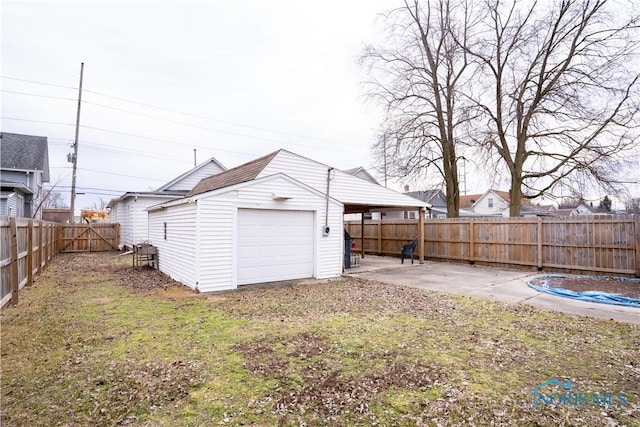 exterior space with a fenced backyard, a garage, an outdoor structure, driveway, and a patio area