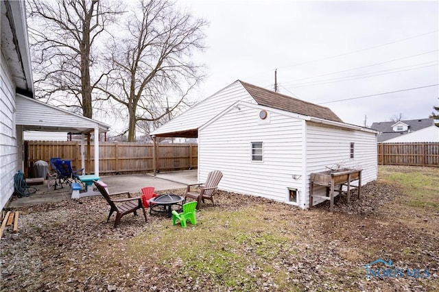 view of yard featuring a patio area, a fenced backyard, an outdoor structure, and a fire pit