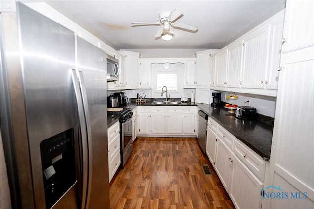 kitchen featuring white cabinets, appliances with stainless steel finishes, dark wood-type flooring, and a sink