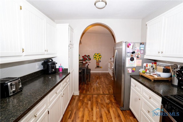 kitchen featuring white cabinetry, arched walkways, and wood finished floors