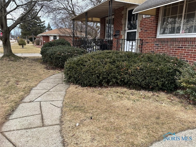 view of side of home with a yard and brick siding