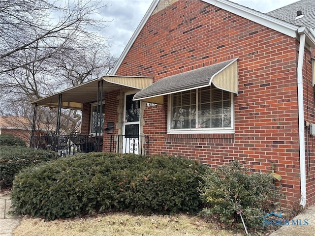 view of property exterior with a shingled roof and brick siding