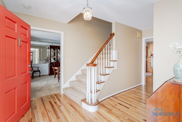 foyer featuring stairs, baseboards, a chandelier, and wood finished floors