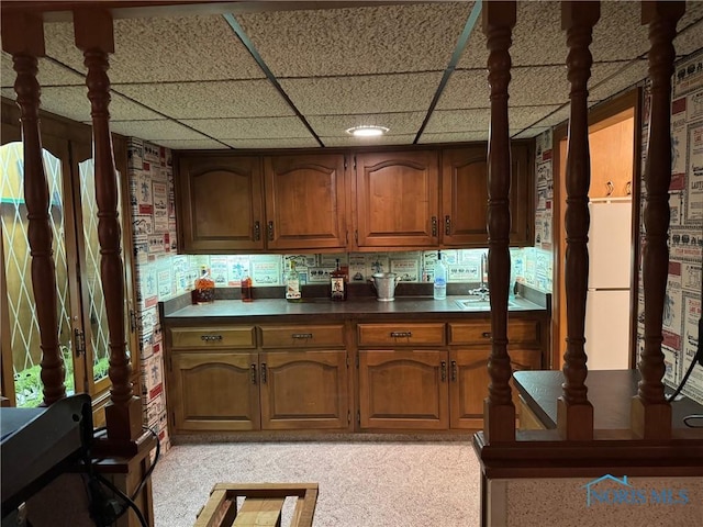 kitchen with dark countertops, brown cabinets, and a drop ceiling