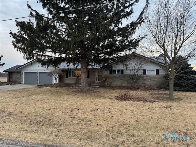 ranch-style house with concrete driveway, stone siding, an attached garage, and a front yard