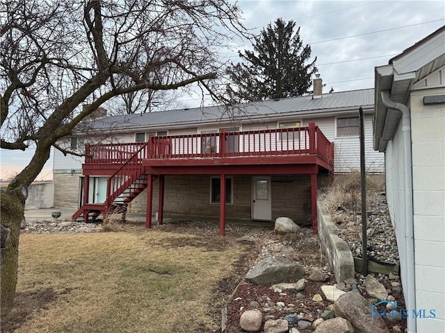 rear view of property featuring a lawn, a chimney, stairway, metal roof, and a wooden deck