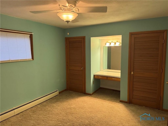 unfurnished bedroom with a baseboard radiator, connected bathroom, light carpet, baseboards, and built in study area