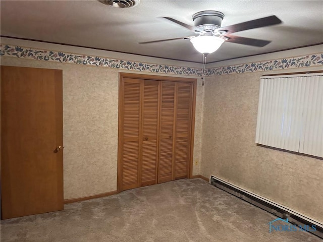 unfurnished bedroom featuring a baseboard heating unit, a closet, carpet flooring, and ceiling fan