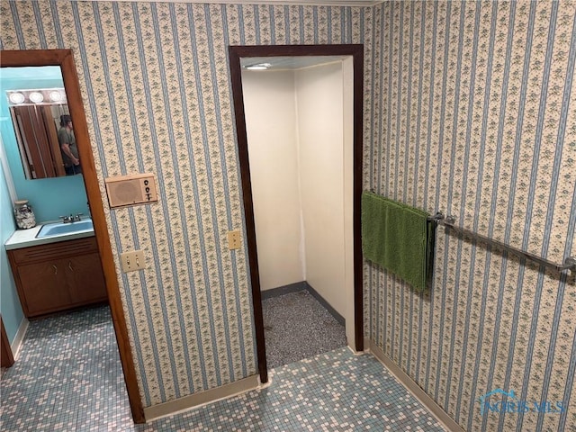 hallway with baseboards, a sink, and wallpapered walls