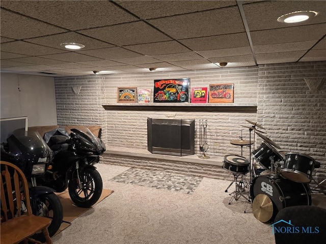 interior space with carpet floors, a paneled ceiling, and brick wall