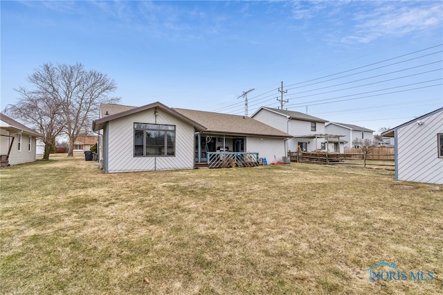 rear view of property featuring fence and a yard