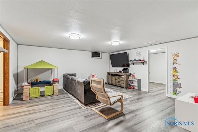 recreation room featuring a textured ceiling, baseboards, and wood finished floors