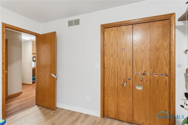 bedroom with baseboards, visible vents, and light wood finished floors