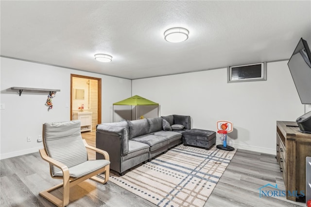 living room with a textured ceiling, baseboards, and wood finished floors