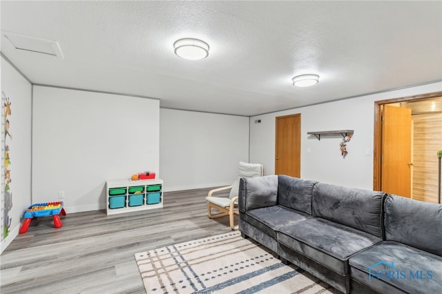 living area featuring a textured ceiling, baseboards, and wood finished floors