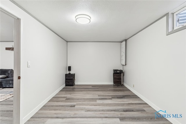 spare room featuring baseboards, light wood-style flooring, and a textured ceiling