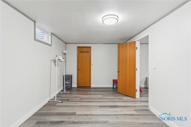 unfurnished room featuring a textured ceiling, wood finished floors, and baseboards