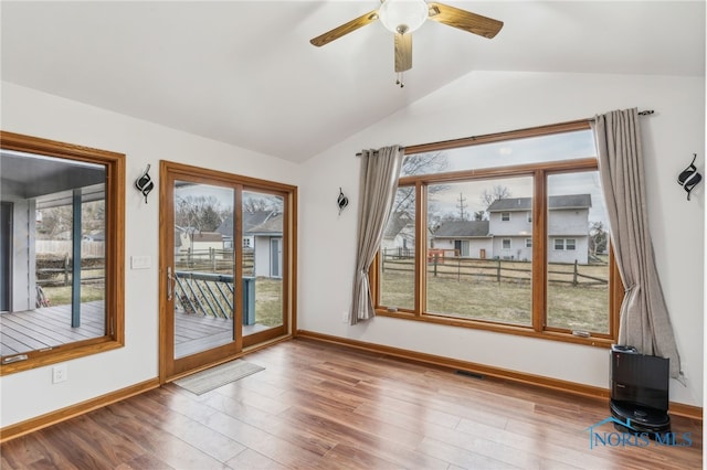 unfurnished room featuring visible vents, vaulted ceiling, baseboards, and wood finished floors