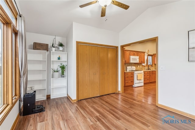 bedroom featuring light wood finished floors, baseboards, a sink, vaulted ceiling, and a closet