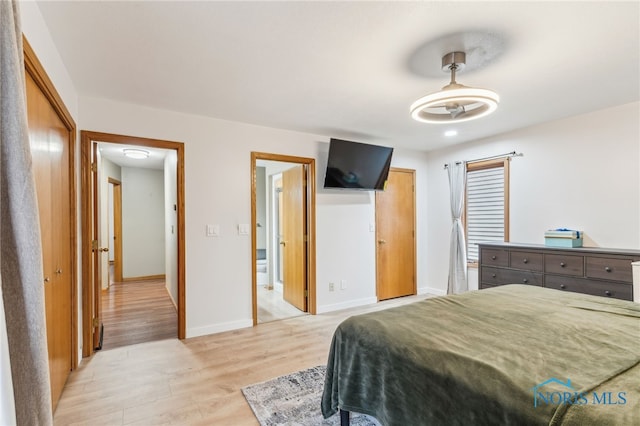 bedroom featuring light wood-type flooring, baseboards, and ensuite bathroom