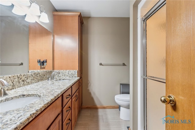 full bath with a shower with shower door, a sink, toilet, and double vanity