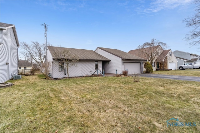 view of front of home featuring driveway, central air condition unit, a garage, and a front lawn