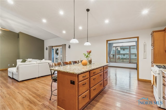 kitchen featuring a breakfast bar area, light wood-style flooring, white range with gas cooktop, open floor plan, and a center island