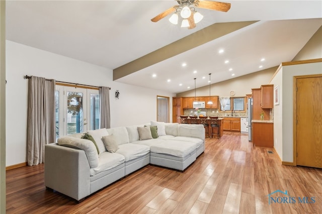 living area featuring lofted ceiling, baseboards, light wood finished floors, and recessed lighting