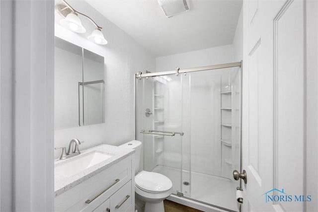 full bathroom featuring toilet, a stall shower, and vanity